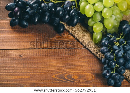 Bunch of white and blue grapes with burlap on wooden background