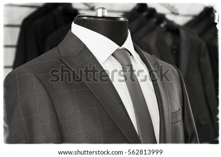 Man's suits: jackets, shirts, ties in a department store. Retro style. Men fashion industry. Nice clothes inside of a shop. Beautiful vintage. Black & White Photography. Old photo. Postcard 