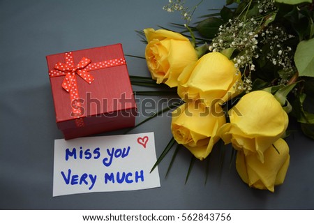 Yellow roses , a gift and miss you very much text on a white note