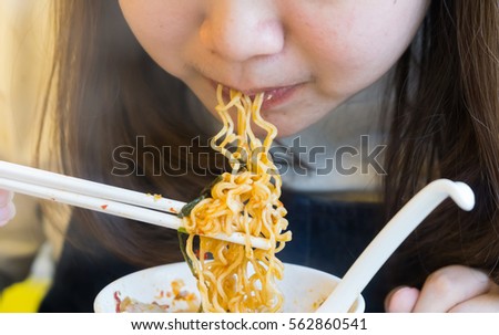 Close up Beautiful women eating asian noodle and still in her mount using white plastic stick Royalty-Free Stock Photo #562860541