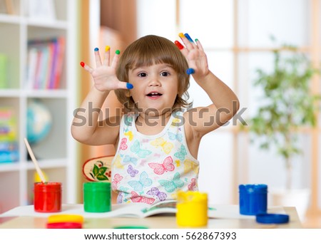 cheerful kid girl showing her fingers painted in bright colors