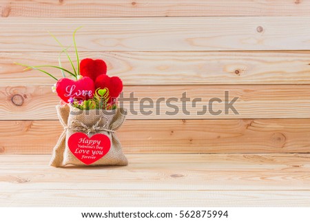 Red heart in burlap sack on wooden table with  background-Valentine day concept.
