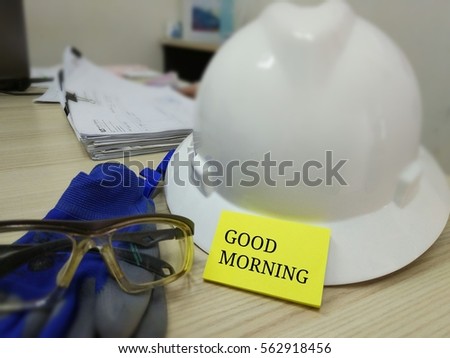 Working concept with safety helmet, safety glass, hand gloves and documents with Good Morning message