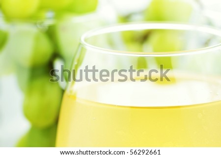 White grape juice in wine glasses with grapes in background. Water drops at 100%.