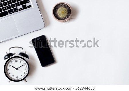 White office desk table with laptop, smartphone, cactus and alarm clock. Top view with copy space, flat lay, 2017