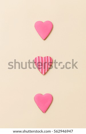 Top view on three little gingerbread cookies in shape of hearts on light yellow background. Flay layout. Love, Valentines's day concept