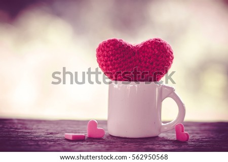 valentine day decoration with white cup of coffee and heart shape on wooden mock up over blurred green garden on day noon light,Image for Happy Valentine holiday concept.