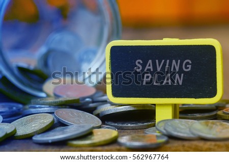 Finance conceptual image with SAVING PLAN words, hundred dollar bills, coins in a jar, a magnifying glass and calculator on wooden background. tone image.