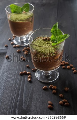 Traditional Italian cuisine. Chocolate tiramisu dessert with tea matcha. Coffee beans. Board for records, black wooden background