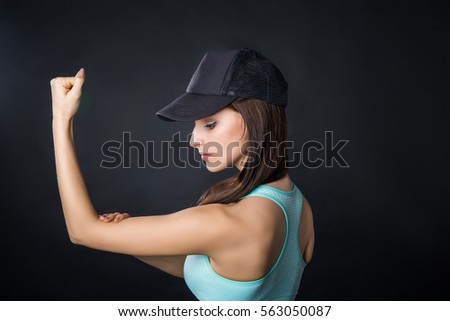 Beautiful sport woman showing biceps on black background