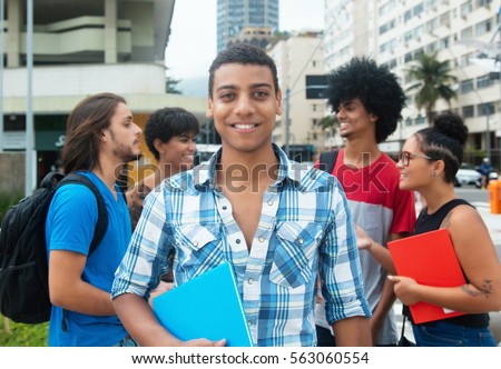 Happy hipster male student with group of multi ethnic young adults in city