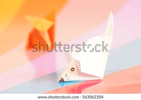 Paper origami fox and mouse are isolated on a colorful background