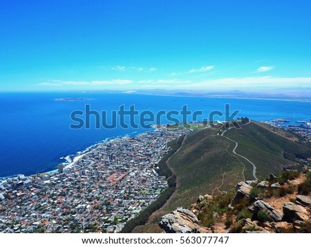 On top of Lion's Head mountain looking to Signal Hill and seascape of Atlantic Ocean and Cape Town cityscape with blue sky and cloud background in South Africa, Table Mountain National Park.