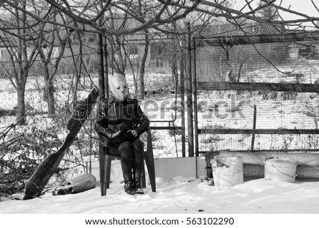 Woman with alien mask in the garden. Winter scene. Black and white photo