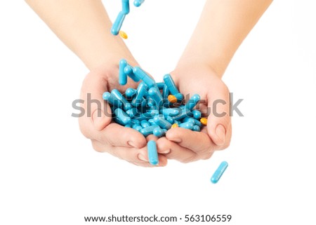 Hands is giving blue capsules and orange pills on white background. Health care concept.