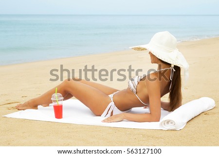 Happy woman wearing hat with a glass of cocktail on the beach