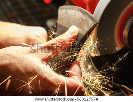 Closeup of hands sharpen the ax sharpening machine  Royalty-Free Stock Photo #563127574