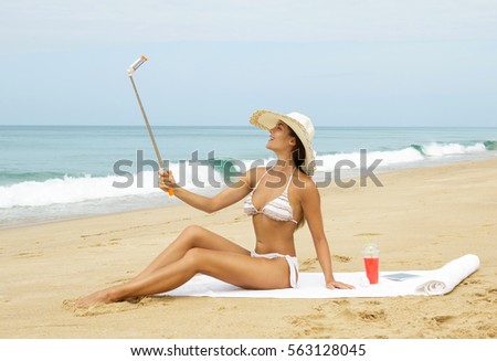 Beautiful woman in hat is taking selfie on the beach
