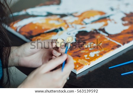 young beautiful girl with long hair draws a picture paints