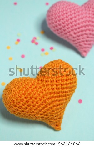 Close up orange and pink crochet heart on polka dots blue background. Love and care concepts. Valentine's day.