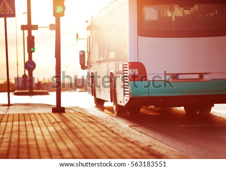 Bus moving on the road in city in early morning. View to the traffic with trafficlights and transport Royalty-Free Stock Photo #563183551