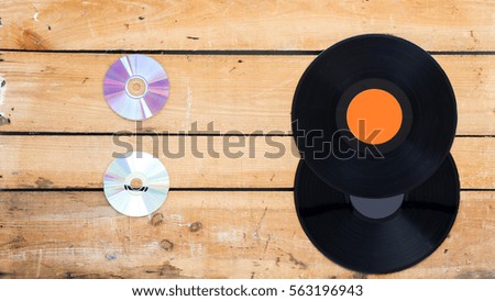 Vinyl records and compact disc on a vintage background facing each other
