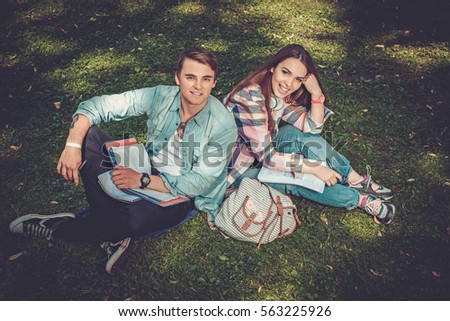 Cheerful couple with studying in green park
