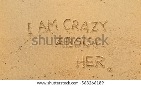 Handwriting words "I AM CRAZY ABOUT HER" on sand of beach