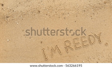 Handwriting words "I'M REEDY" on sand of beach
