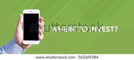 Smart phone in hand front of green background and written WHERE TO INVEST?