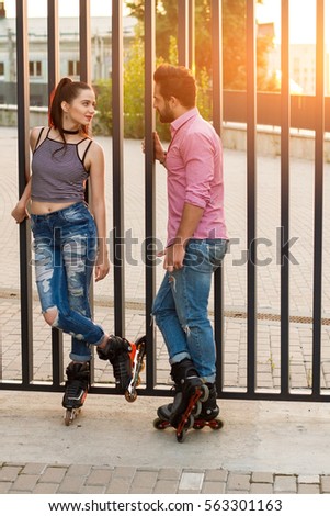 Couple on inline skates standing. Young woman looking at man. Date of active people.