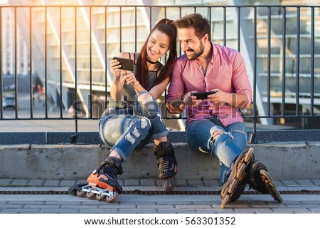 Man and woman with phones. Girl on inline skates smiling. Posting photos on the internet.
