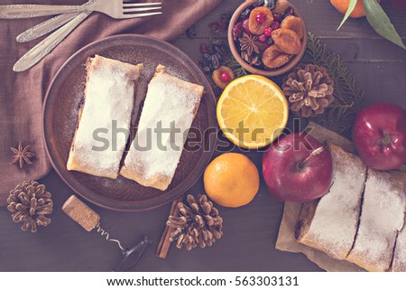 Apple strudel (pie) with dried fruits, oranges, cranberries, walnuts with sugar  on dark background.   Lunch, dinner for two. Romantic dinner.