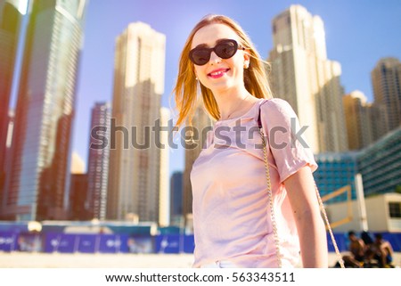 Colorful picture of stunning lady with pink lips posing before skyscrapers in Dubai