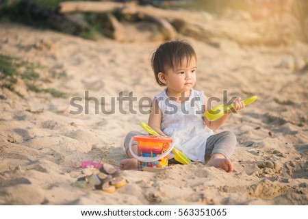 Little girl building sandcastle with kids toys on the beach.