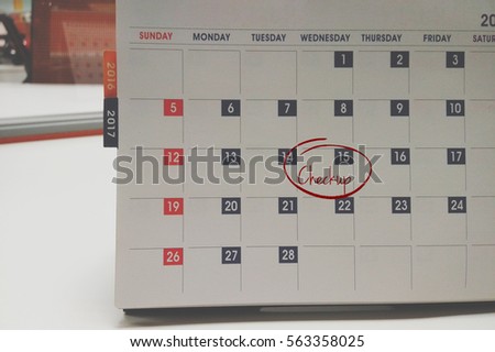 A concept image of a table calendar over a blur background with red circle and a word Checkup