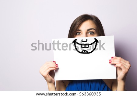 Happy and smiling girl with a smile painted on paper