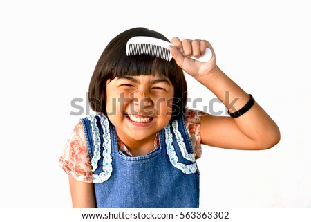 Asian female kid brushes hair on white background, selective focus