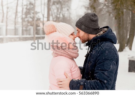Portrait of young couple man and woman kissing in background of christmas tree with snow in winter Park