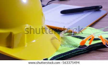 Closeup of safety glass and yellow safety helmet with blur touch pad.Selective focus