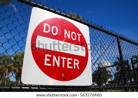 Red and White Do Not Enter Sign on Chain Link Fence with Deerfield Beach, Florida Identifying Water Tower in the Background Frame Right, Quiet Waters Park, Sunny Morning with Clear Blue Sky