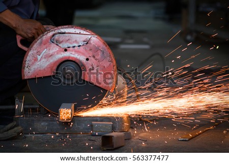 Workers use machine for cutting metal with spark light.