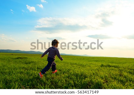 Young child running through a meadow Royalty-Free Stock Photo #563417149