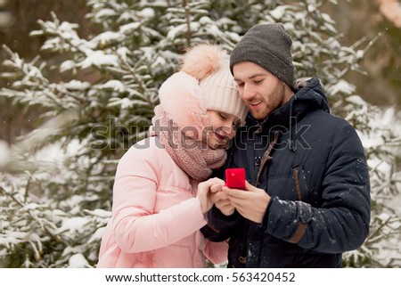 Portrait of young couple man and woman kissing in background of christmas tree with snow in winter Park