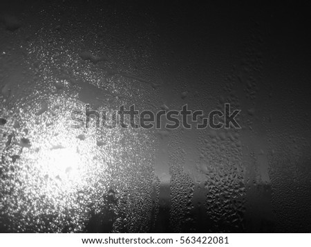 Blurry natural water drops on sunshine frozen window glass background surface, closeup