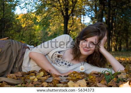Girl lying on autumn leaves in park