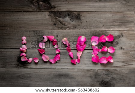 valentine concept. Love word from pink rose petals on white wooden background.