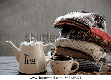 Knitted sweaters,teapot  and a cup of coffee on a wooden table.