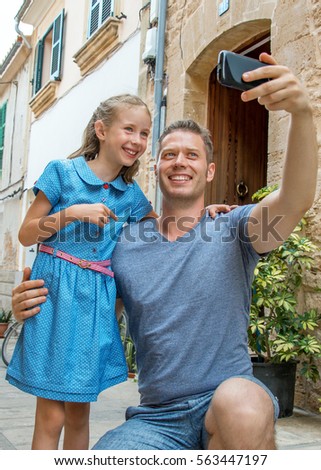 Father and daughter taking selfie in old town.