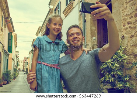 Father and daughter taking selfie in old town. Vintage effect.